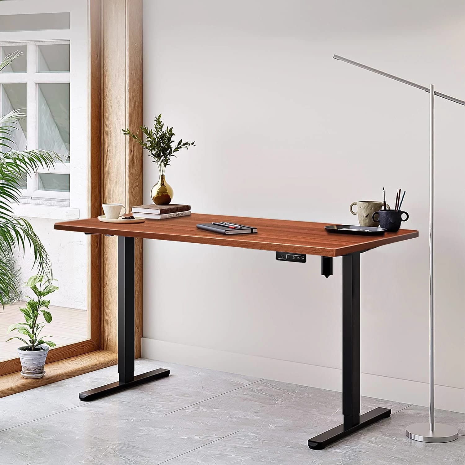 A KosmoCare walnut electric sit-stand desk in a styled room with a tall window behind it